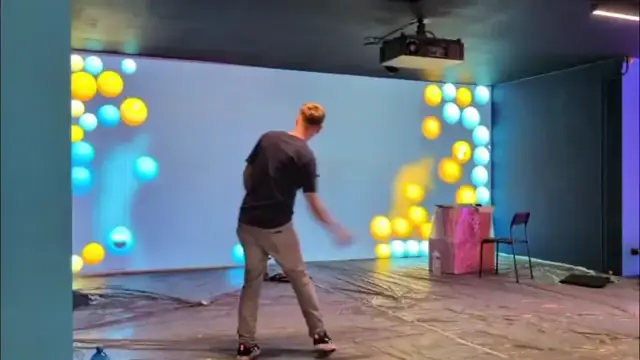 Someone playing with projected spheres on a wall
